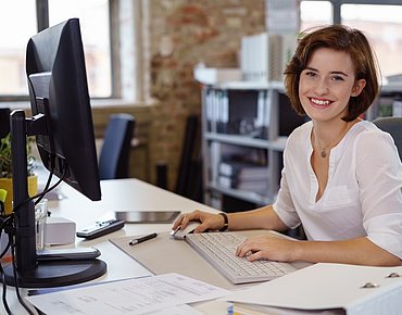 Junge Frau an ihrem Arbeitsplatz im Büro