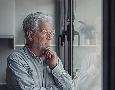 Älterer Mann schaut aus dem Fenster
