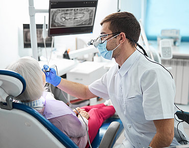 Zahnarzt untersucht die Zähne einer älteren Dame