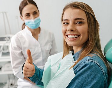Frau beim Zahnarzt zeigt Daumen hoch